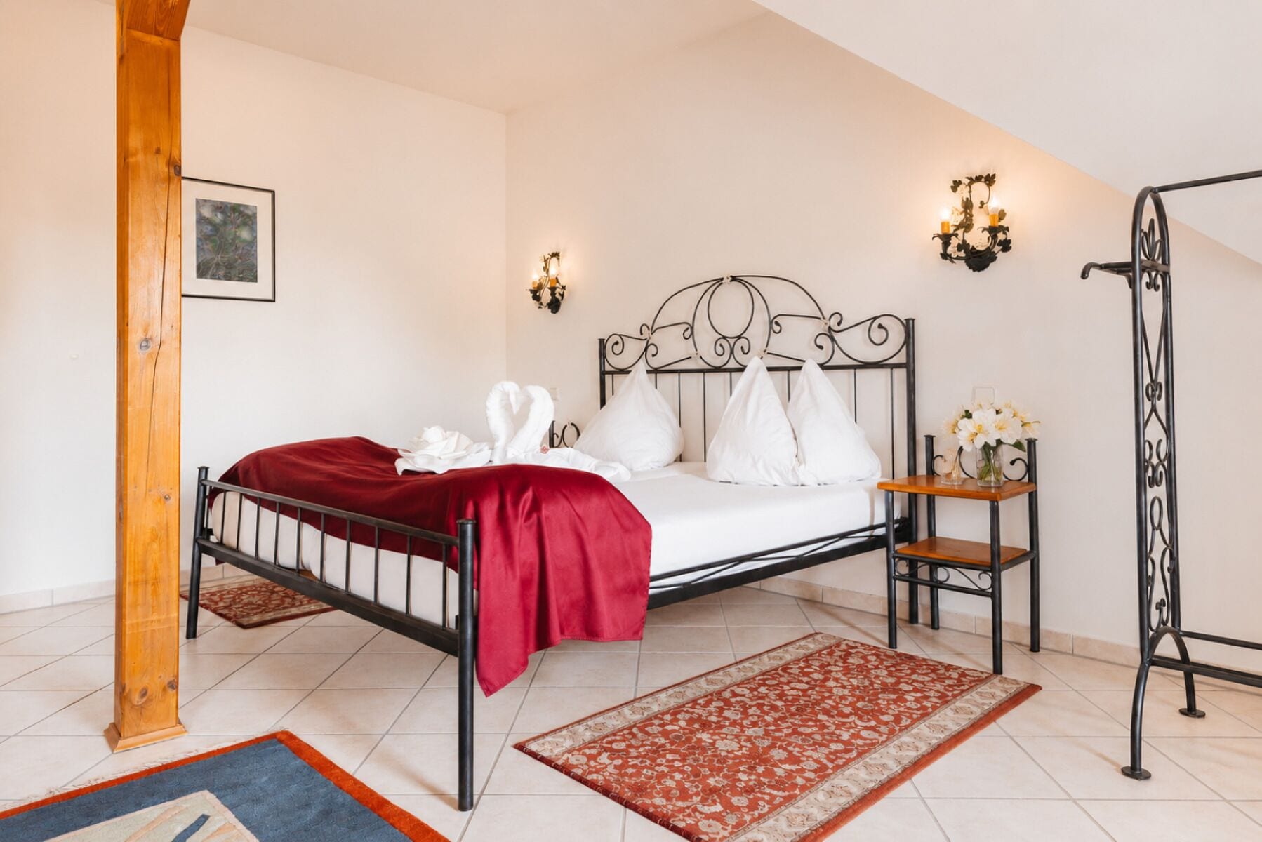 Een keurig opgemaakt slaapkamer met een bed, een nachtkastje, een wandlamp en een ingelijste foto aan de muur.