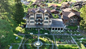 A large, multi-story building with a symmetrical facade, surrounded by lush gardens and a central fountain.
