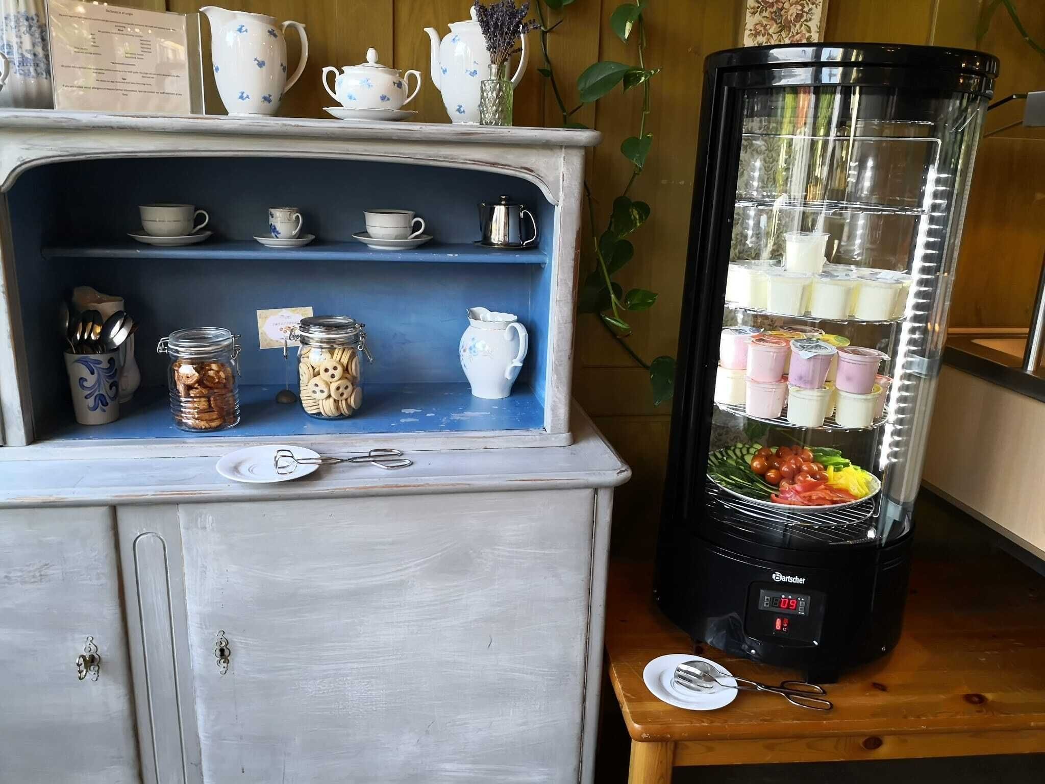 Eine Küchenzeile mit Kaffeemaschine, Mixer und einem Regal mit Gläsern und Tassen.