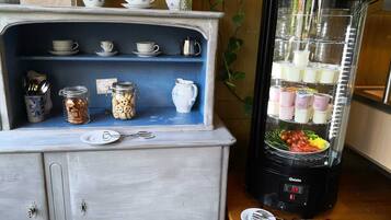 Eine Küchenzeile mit Kaffeemaschine, Mixer und einem Regal mit Gläsern und Tassen.