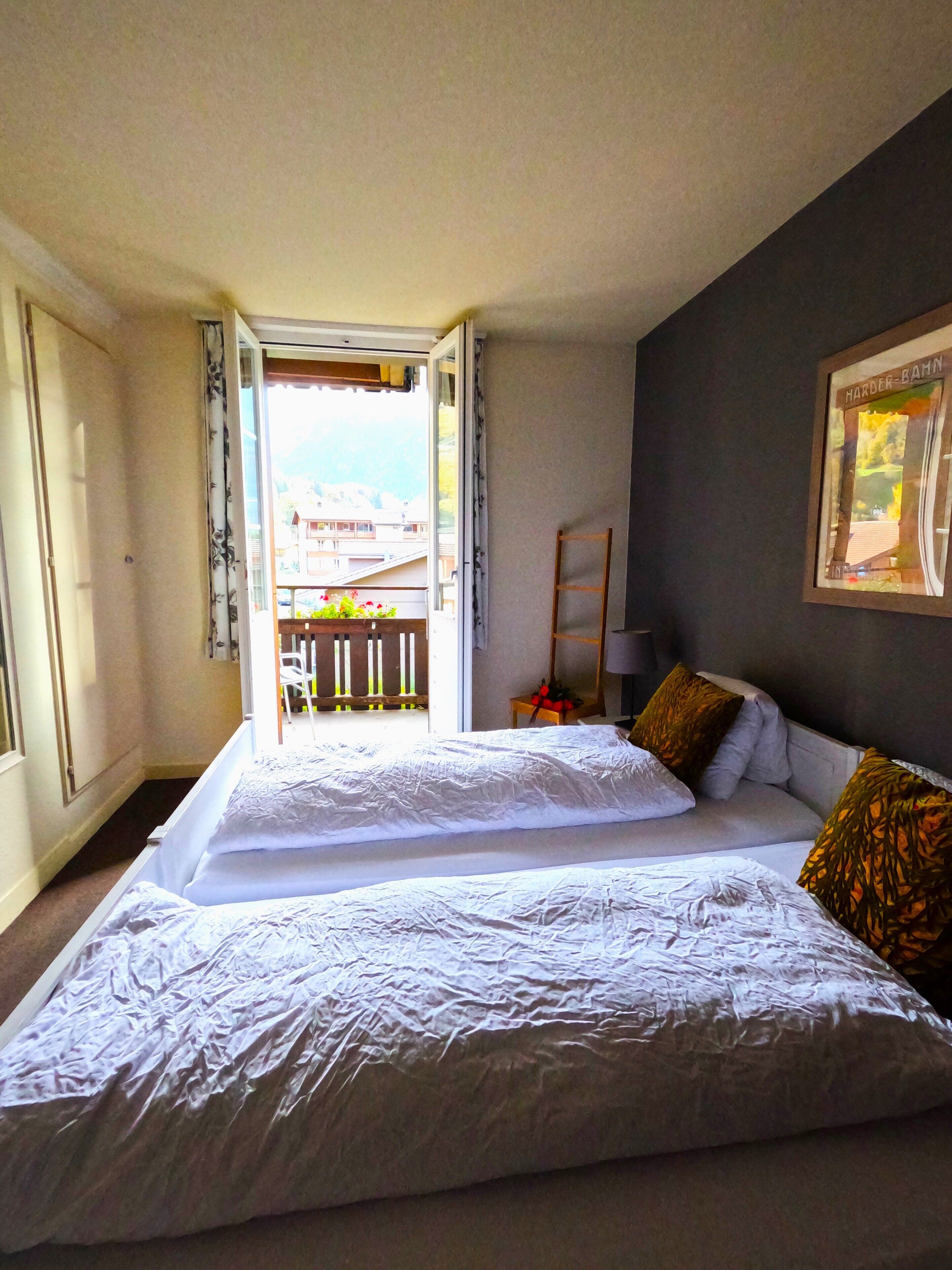 Une chambre d’hôtel avec deux lits, un balcon et un tableau encadré au mur.