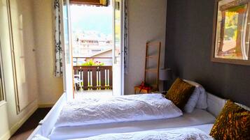 Une chambre d’hôtel avec deux lits, un balcon et un tableau encadré au mur.