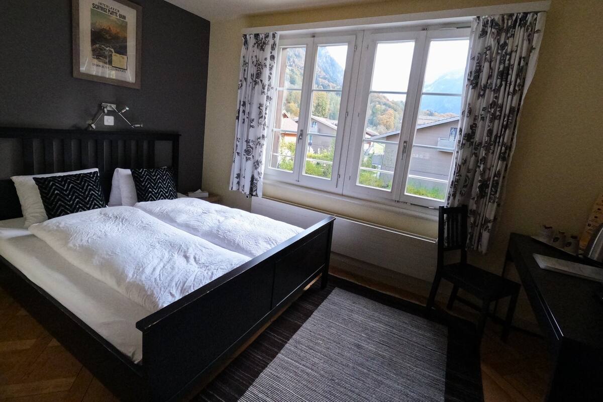 Une chambre à coucher avec un lit, un bureau et une fenêtre avec des rideaux.