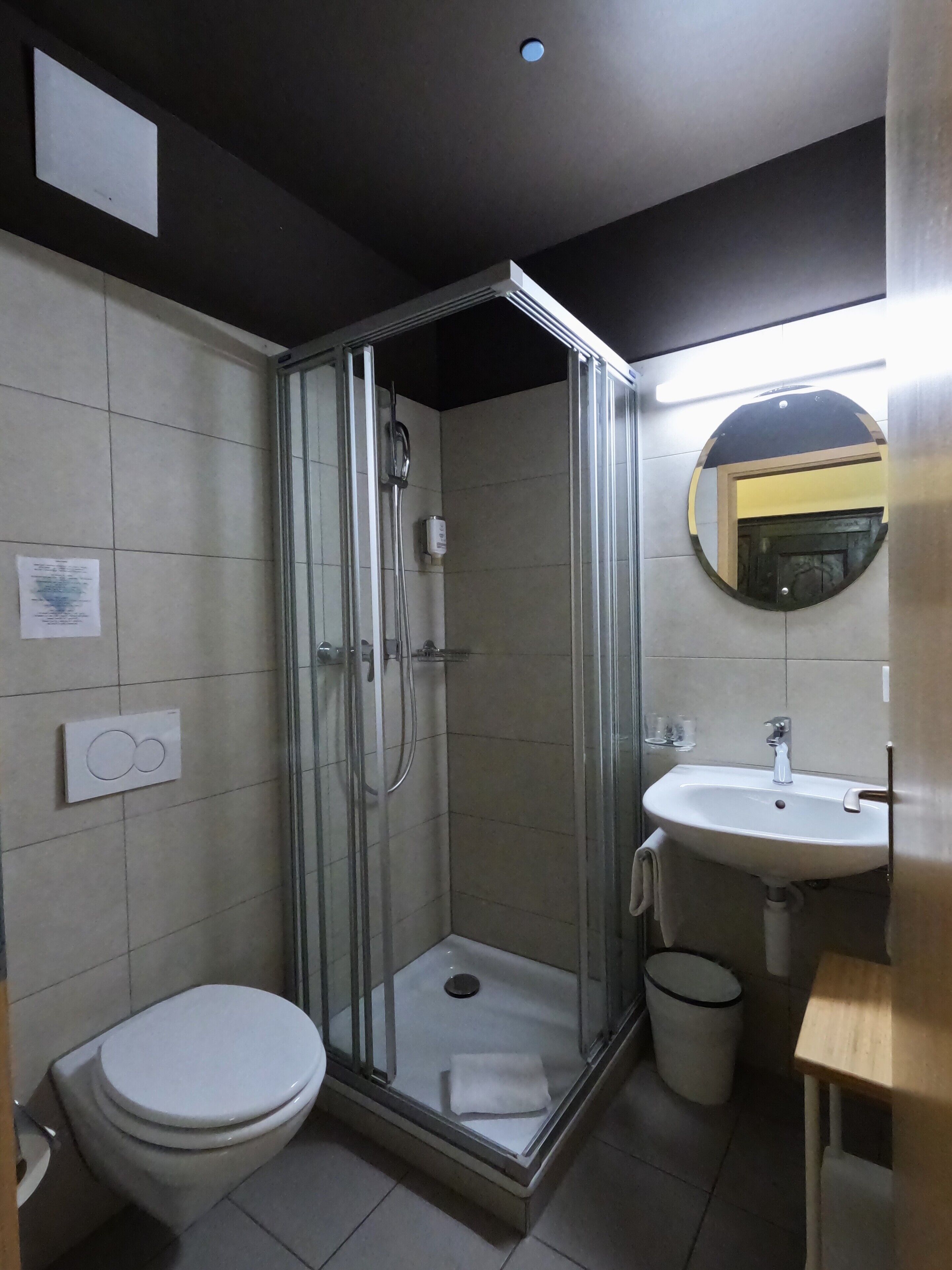 A modern bathroom with a glass-enclosed shower, a white sink, and a toilet.