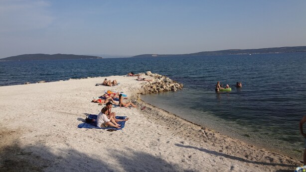 A beach with people sunbathing and swimming. - Villa Cezar (Kastela)