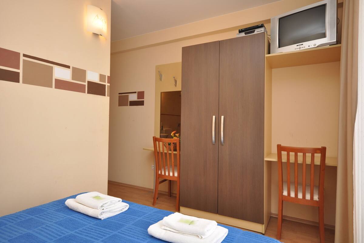 A room with a bed, a wardrobe, a television, and a chair.