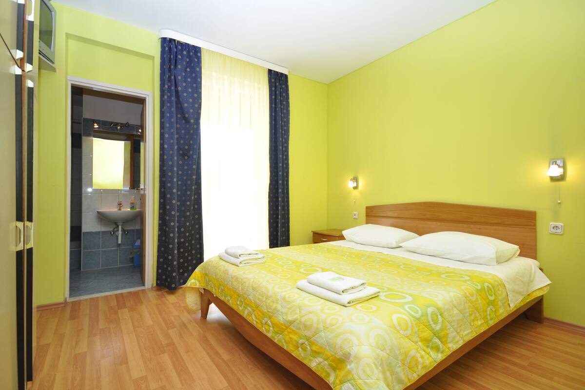 A room with a bed, a bathroom, and a mirror.