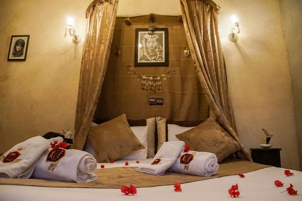 A hotel room with a bed, curtains, and a framed picture on the wall.