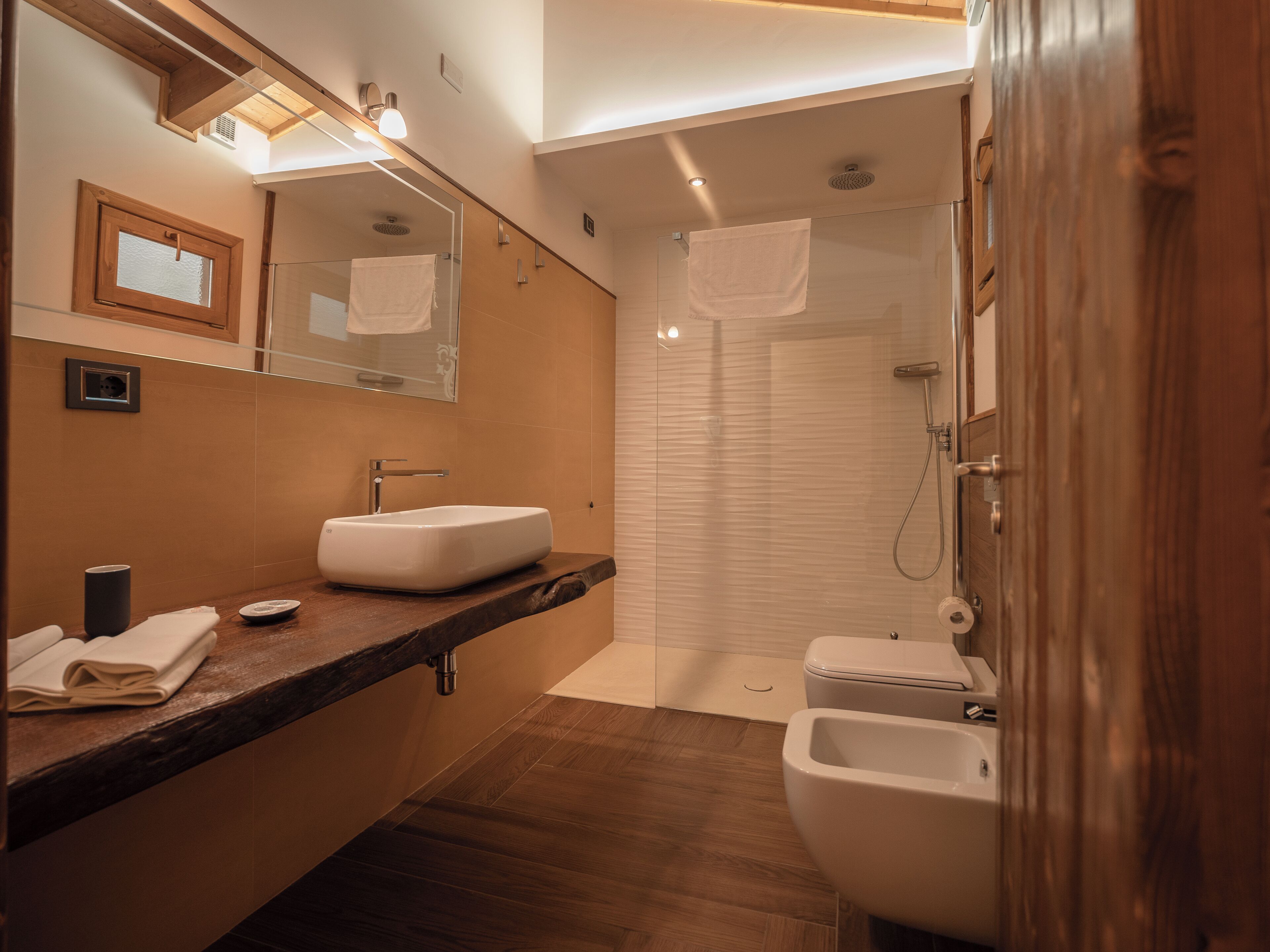 A modern bathroom with a large mirror, a sink, a toilet, and a shower.