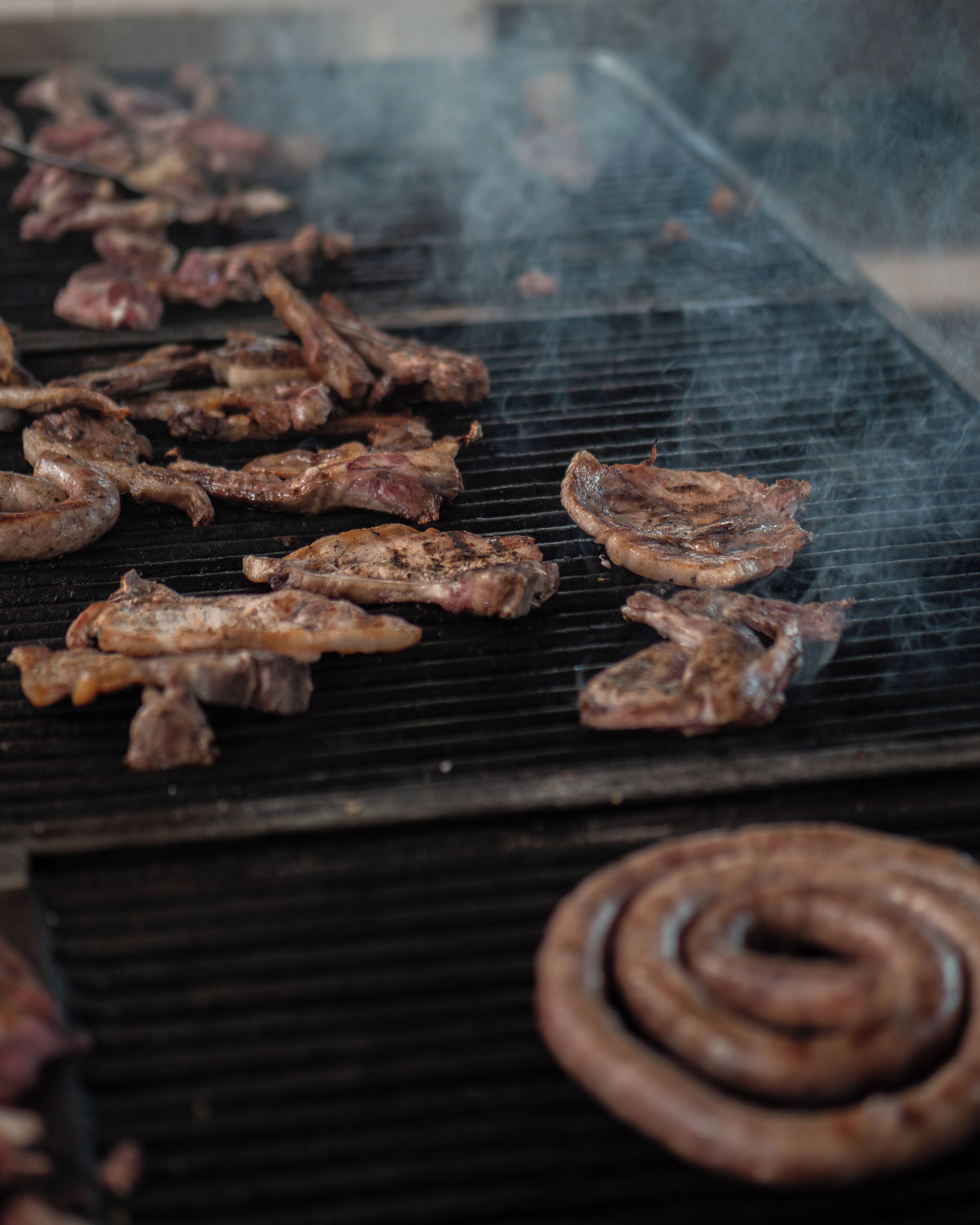 A grill with various meats cooking.