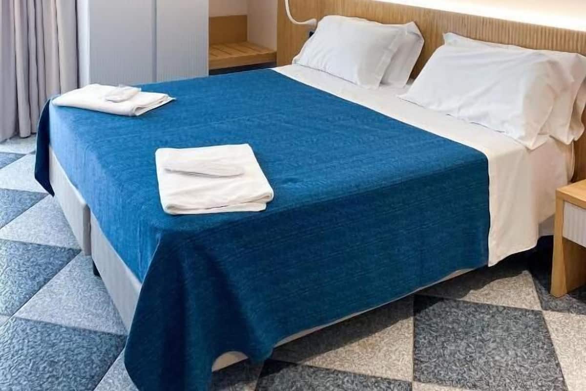 Une chambre d’hôtel comprenant un lit, une table de chevet, une armoire et une salle de bain.