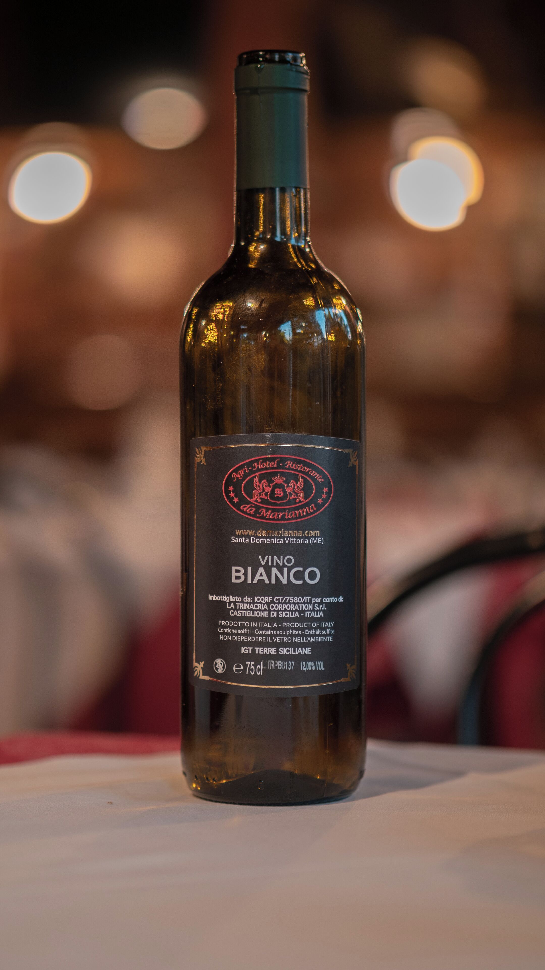 A bottle of Vino Bianco on a table with a blurred background.