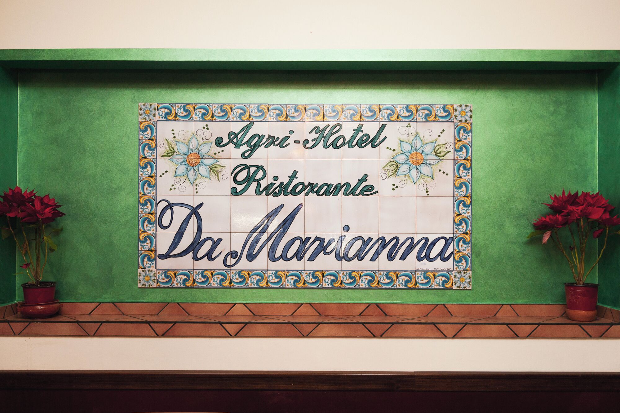A tiled sign with the text "Agri-Hotel Restaurante Da Marianna" surrounded by decorative tiles.