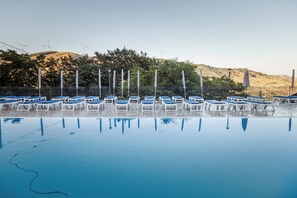 An infinity pool with blue lounge chairs and a view of wind turbines in the background. - Agri Hotel da Marianna (Santa Domenica Vittoria)