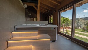 Een moderne badkamer met een houten trap, een ruim bad en uitzicht op de omgeving.