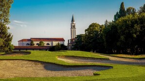 Um campo de golfe com uma igreja e uma torre ao fundo.