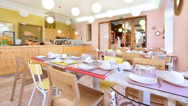 Un restaurante con varias mesas dispuestas para comer, sillas de madera y lámparas colgantes.