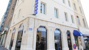 Un hotel de estilo arquitectónico clásico, con una entrada destacada que incluye un toldo azul y un cartel que indica que es un hotel.