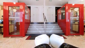 Un interior moderno con una escalera, puertas de vidrio con marco rojo y un diseño minimalista.