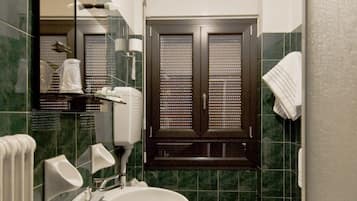 A bathroom with a white sink, two toilets, a mirror, and a towel rack.