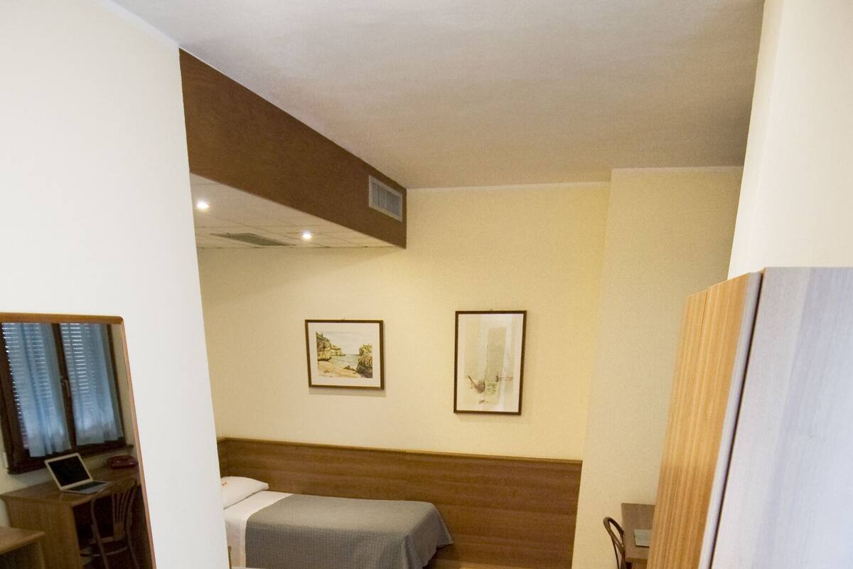 Habitación de hotel con dos camas, un escritorio con una computadora portátil y dos cuadros en la pared.