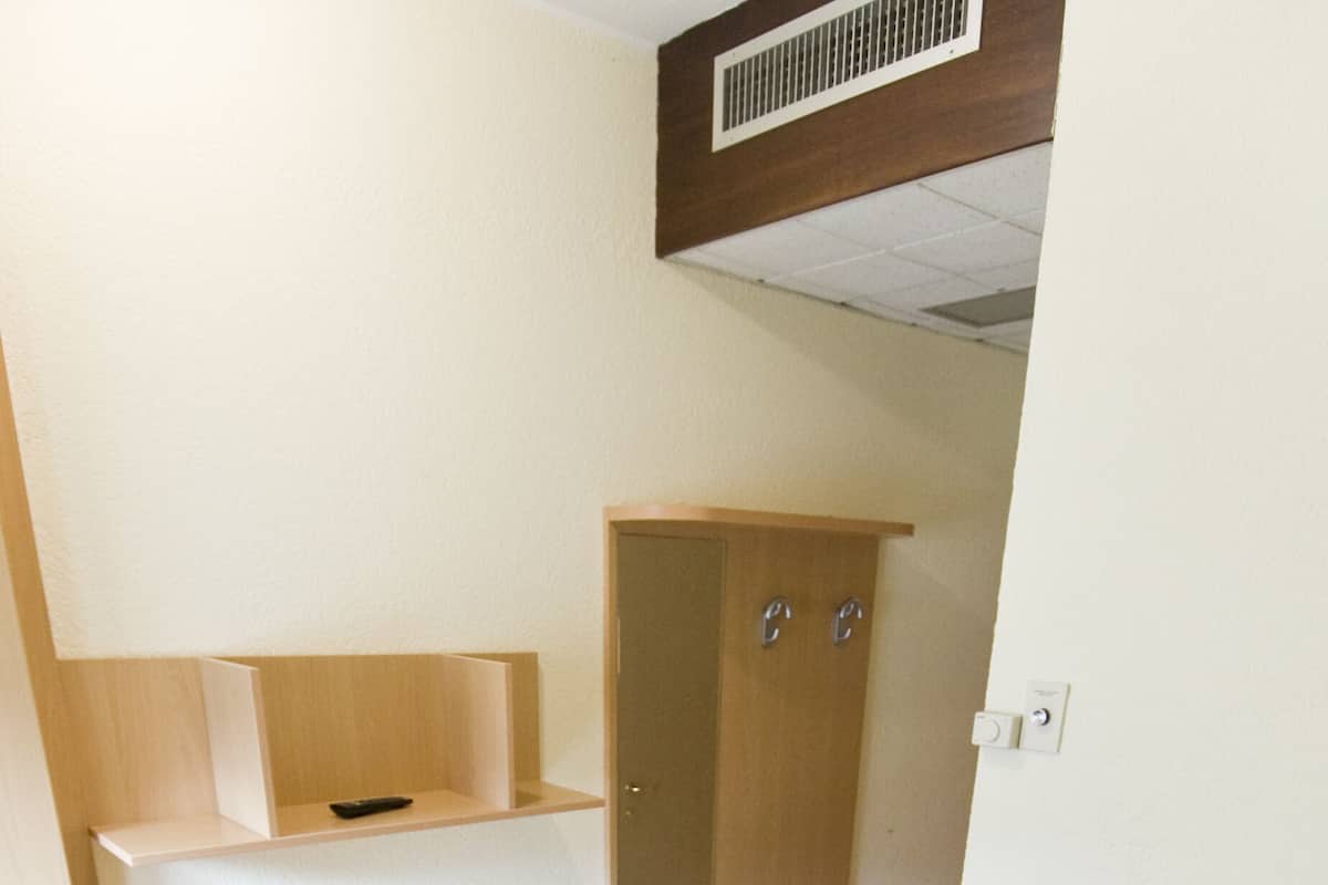 Una habitación pequeña con escritorio, silla y una maleta negra.