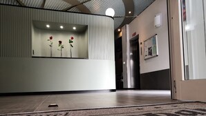 A reception area with a modern design, featuring a reception desk, a wall-mounted flower display, and a sign on the floor. - Europa (Sondrio)