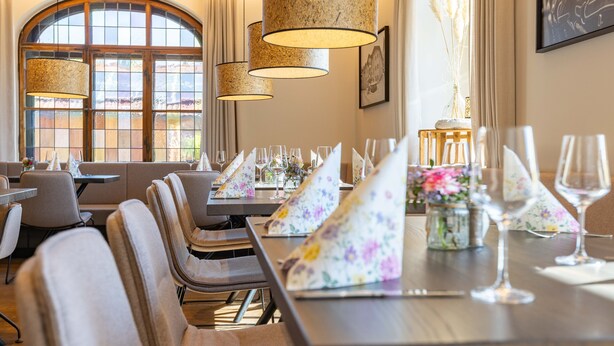 A dining area with tables set for a meal, featuring floral napkins and glassware. - Hotel am Wald (Bad Toelz)