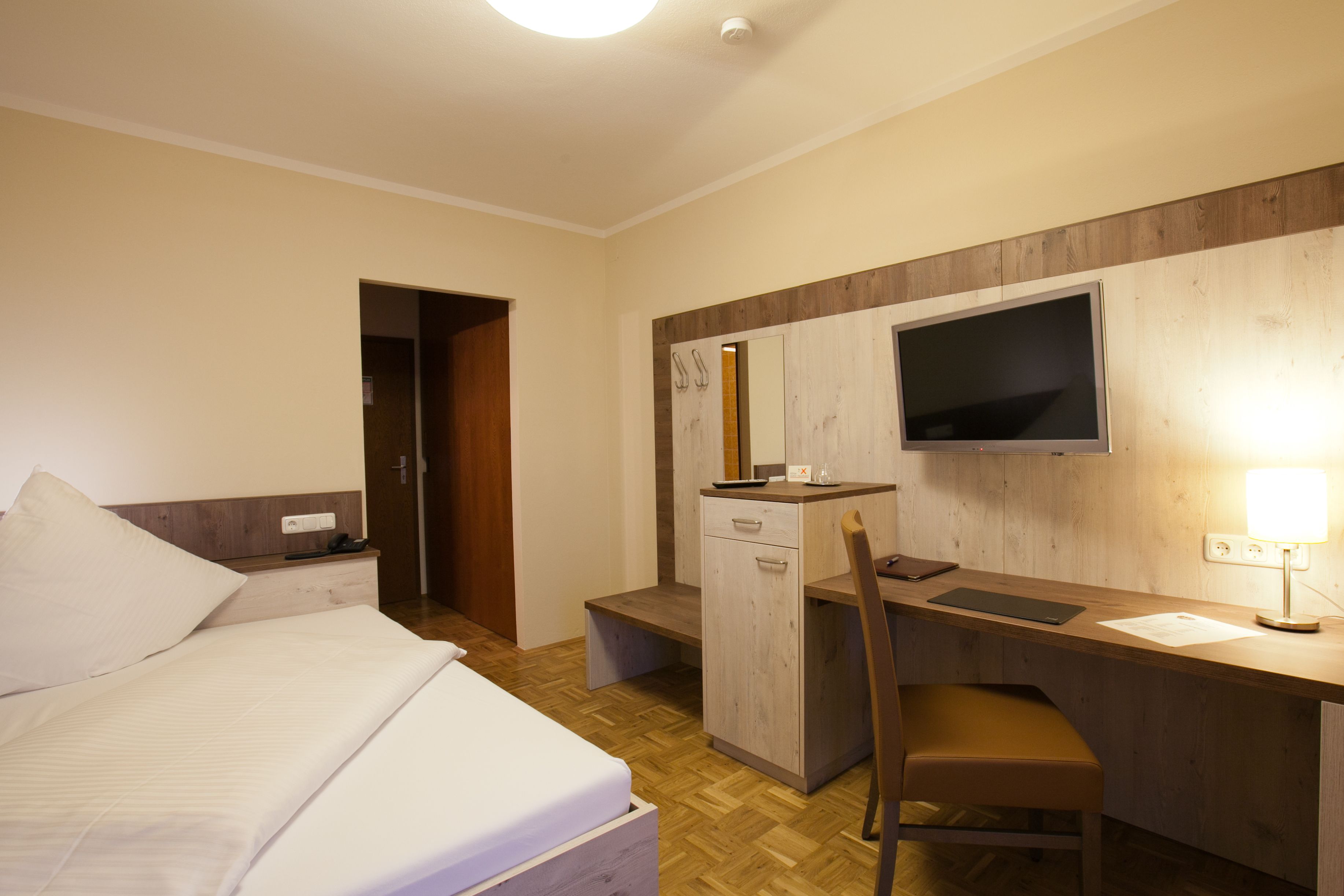 Une chambre d’hôtel équipée d’un lit, d’un bureau, d’une chaise, d’une télévision et d’une lampe de bureau.