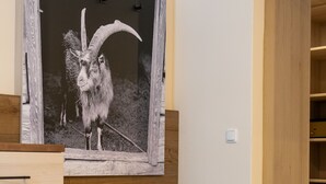 A bedroom with a wooden bed, a large framed picture of a goat, and a wooden wardrobe. - Hotel am Wald (Bad Toelz)