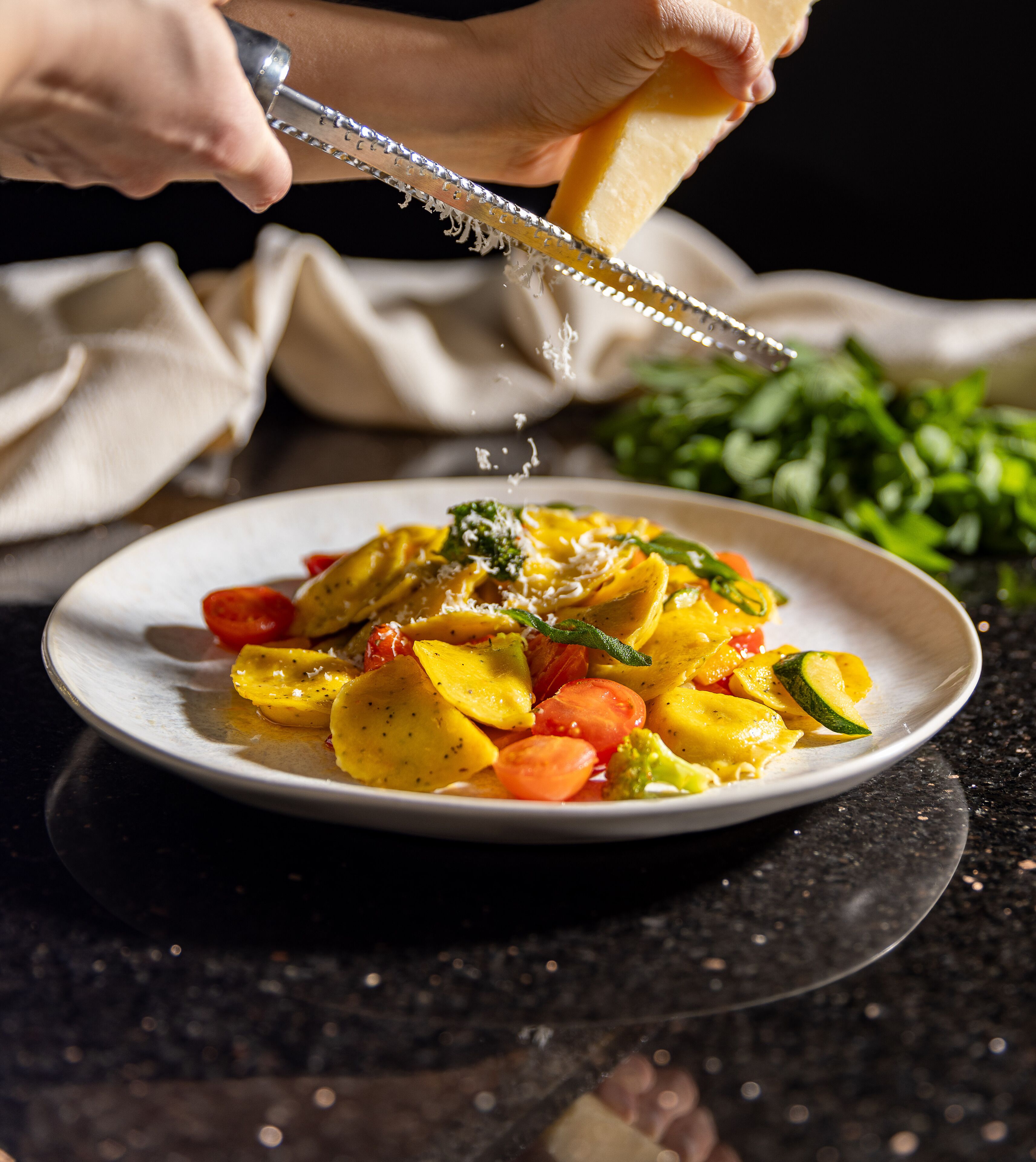 A plate of food with vegetables and cheese being grated.