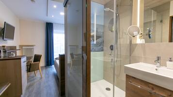 Une salle de bain moderne avec une douche à parois de verre, un lavabo avec un miroir et un meuble-lavabo en bois.