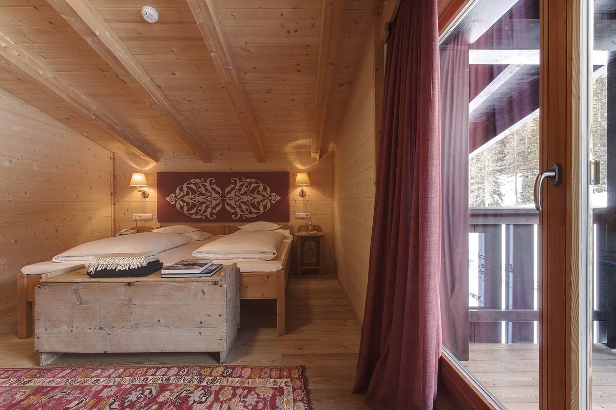A cozy wooden cabin bedroom with a bed, bedside lamps, and a decorative wall piece.