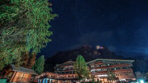 A lodge with multiple floors, outdoor seating, and a mountain backdrop. - Ciasa Salares (Badia)