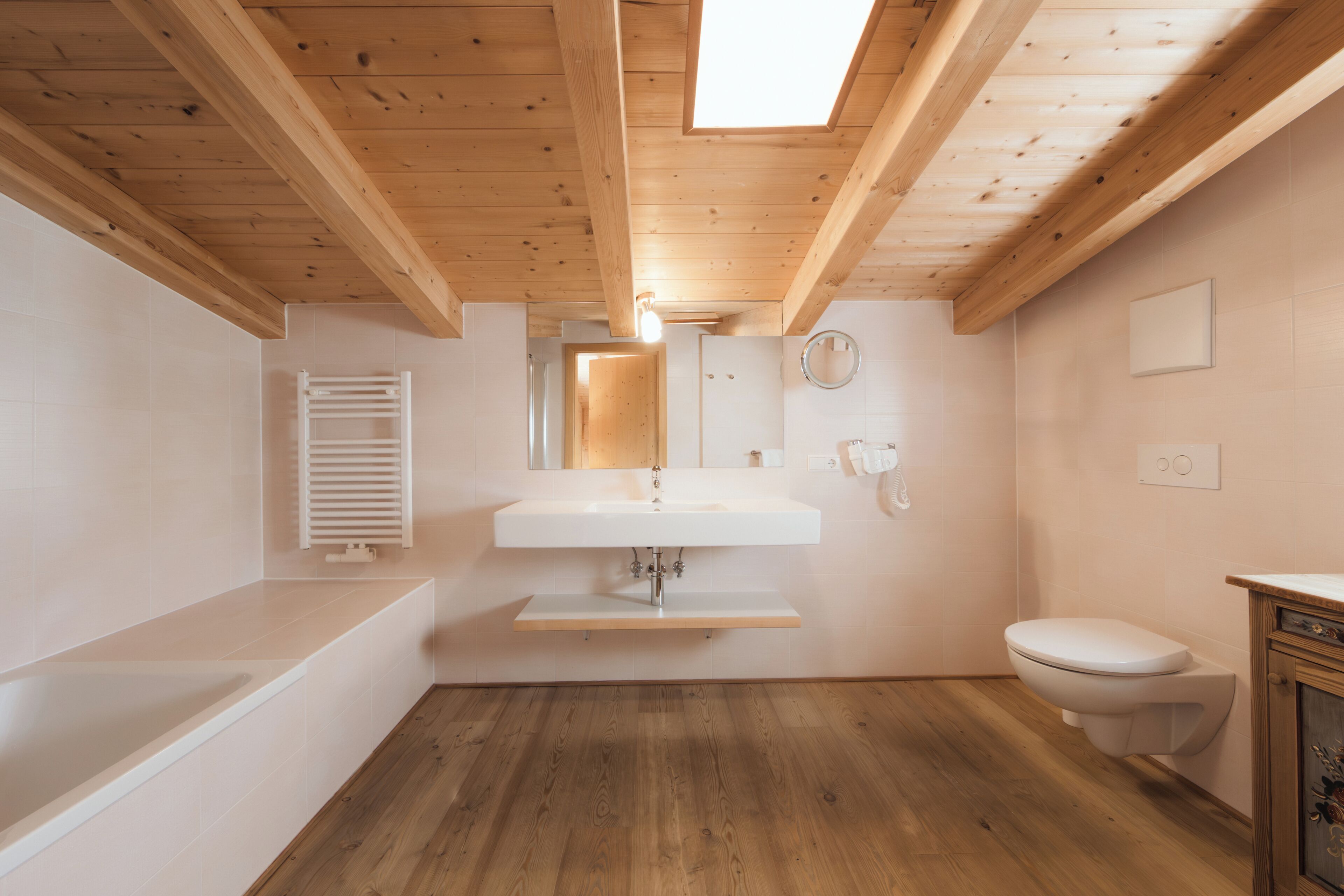 A modern bathroom with a wooden ceiling, a built-in sink, a toilet, and a shower area.