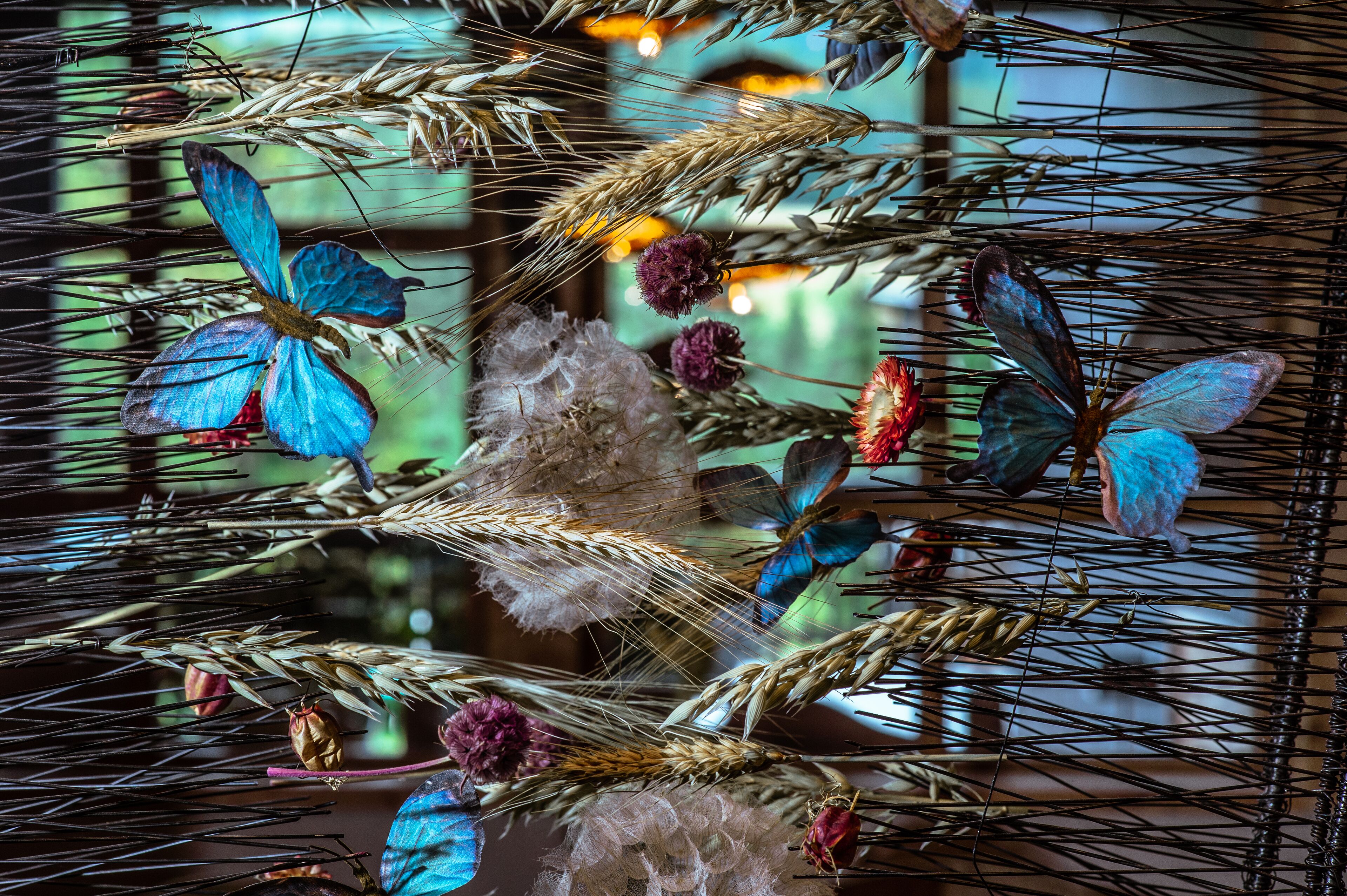 A decorative arrangement of wheat stalks and artificial butterflies.