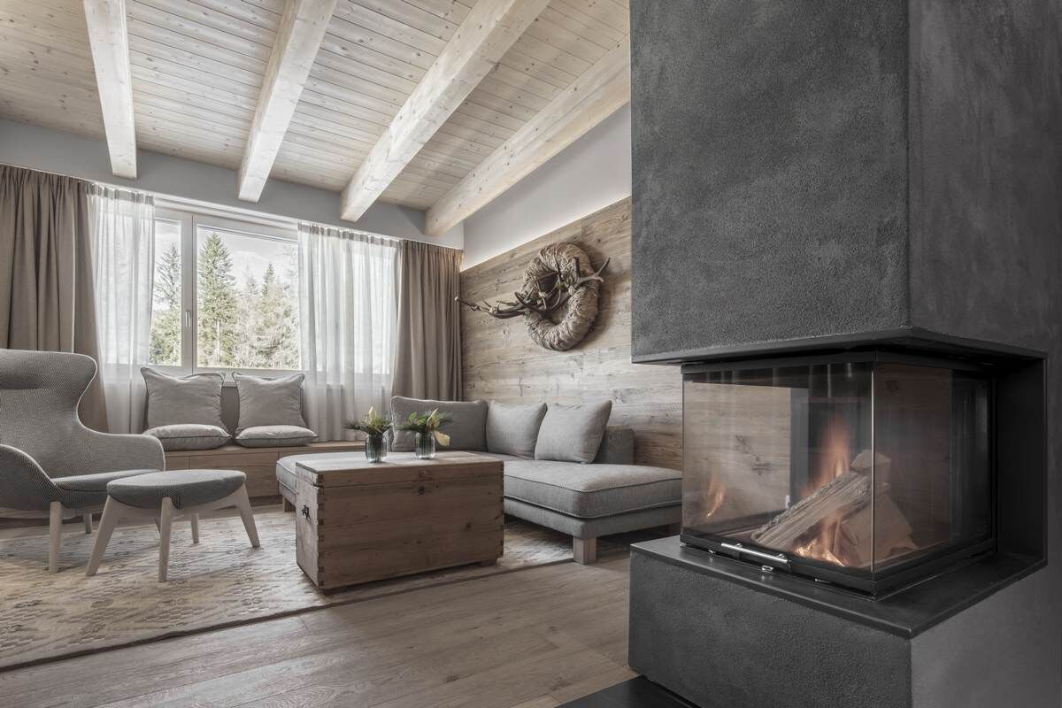 Un soggiorno moderno con camino, travi in legno, un divano e una grande finestra.