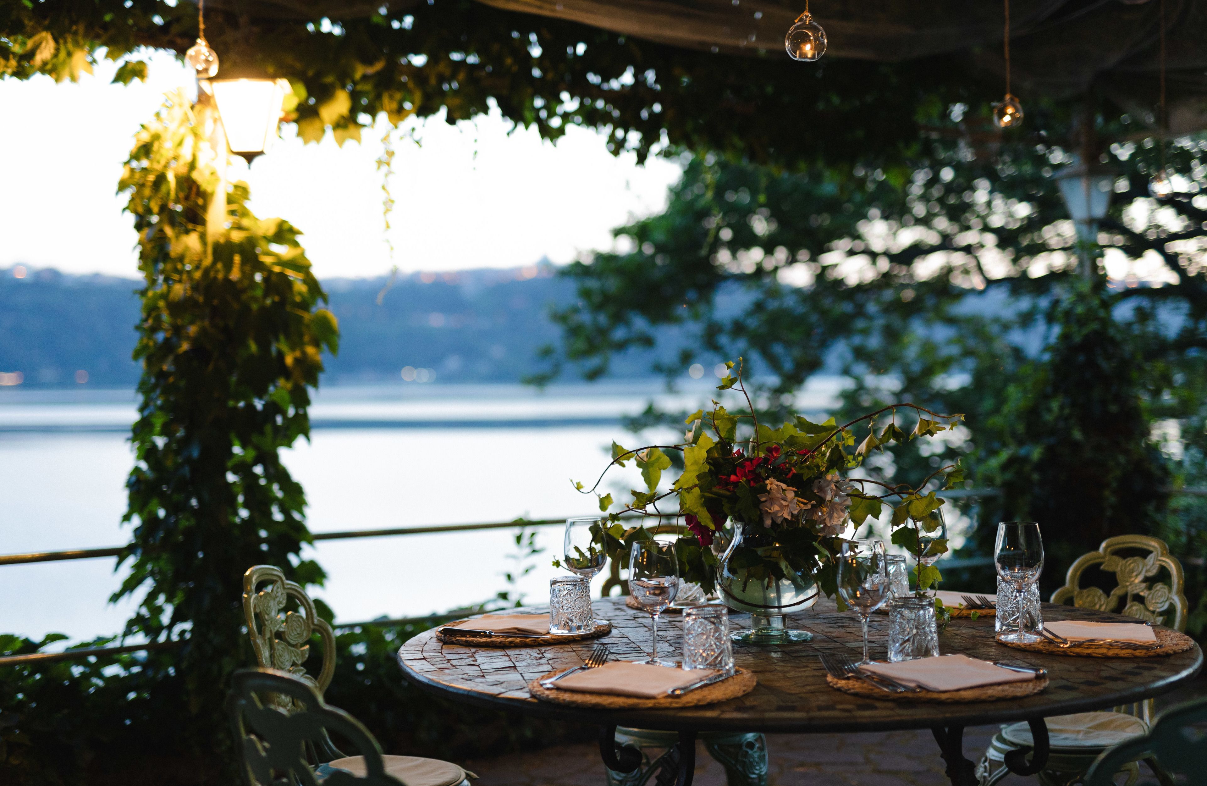 A round dining table set for six with a vase of flowers, glasses, and cutlery.