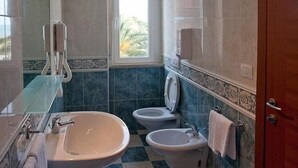 A bathroom with a bathtub, two sinks, and a toilet. - Ambassador (Tortoreto)