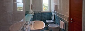 Un baño con bañera, dos lavamanos y un inodoro.