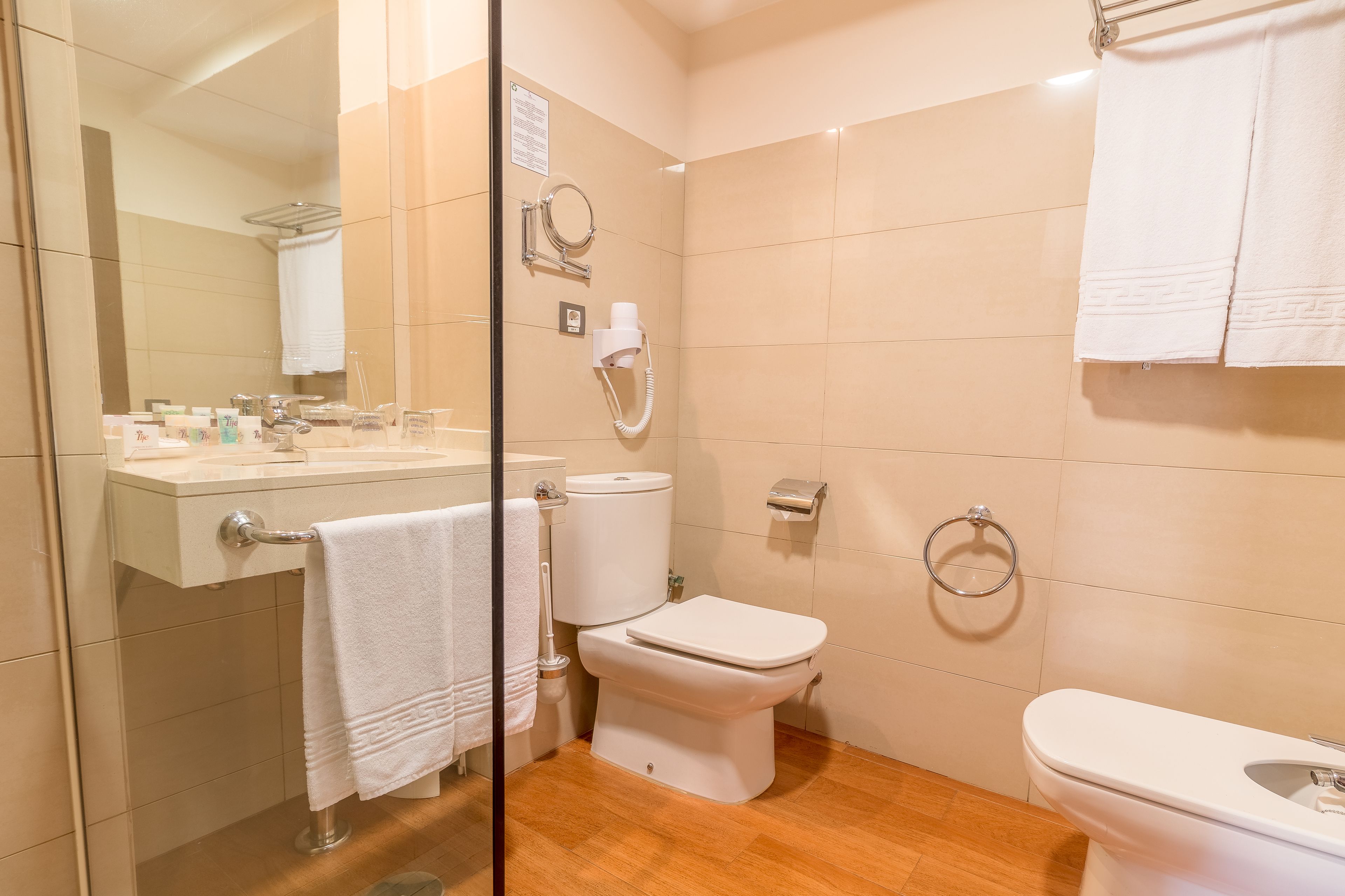 Een moderne badkamer met toilet, hygiëneschuimer en wastafel.
