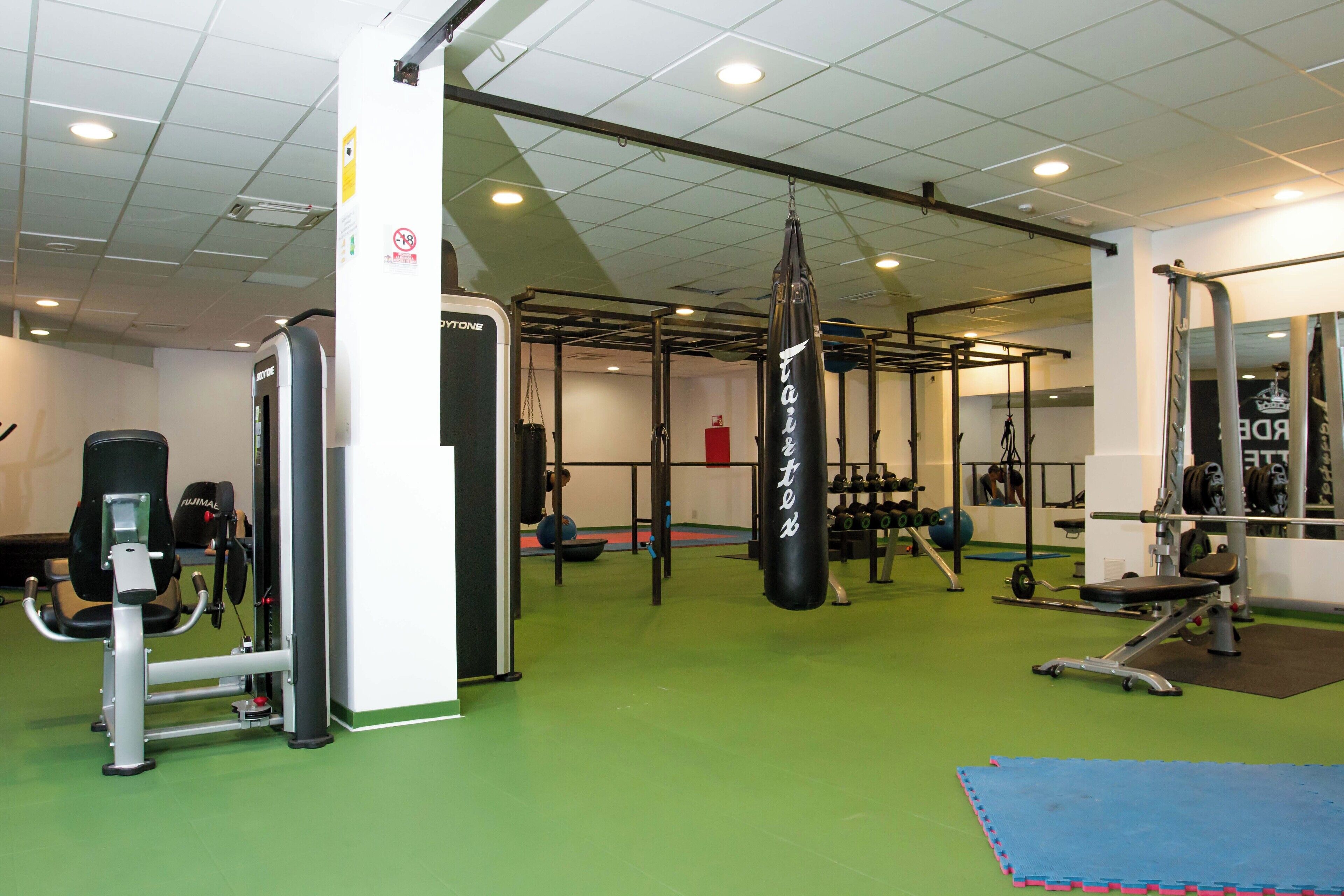 Une salle de sport équipée de matériel d’exercice, d’un sac de frappe et d’un banc de musculation.