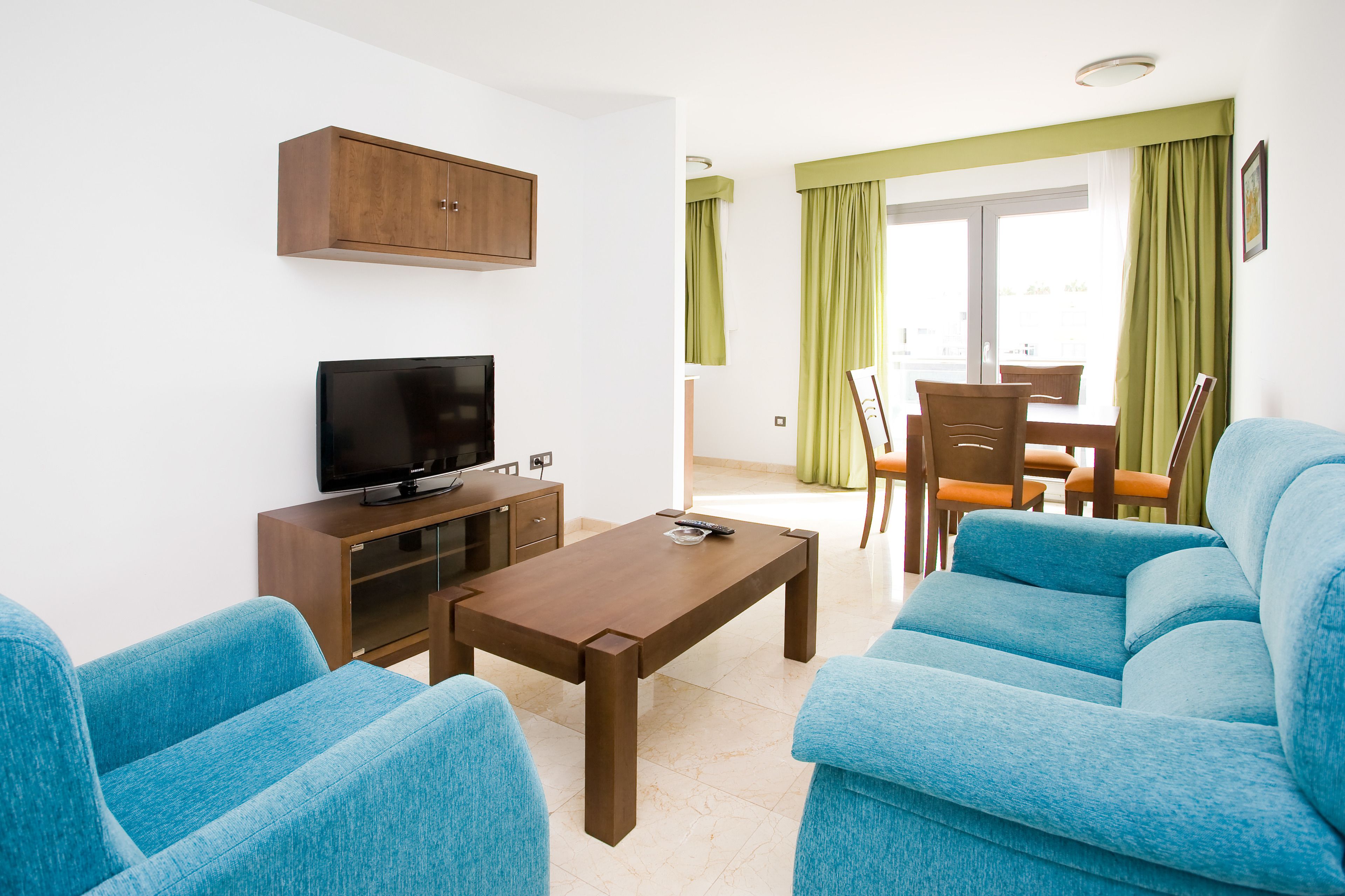 Una sala de estar con televisor, mueble de madera y sofá azul.