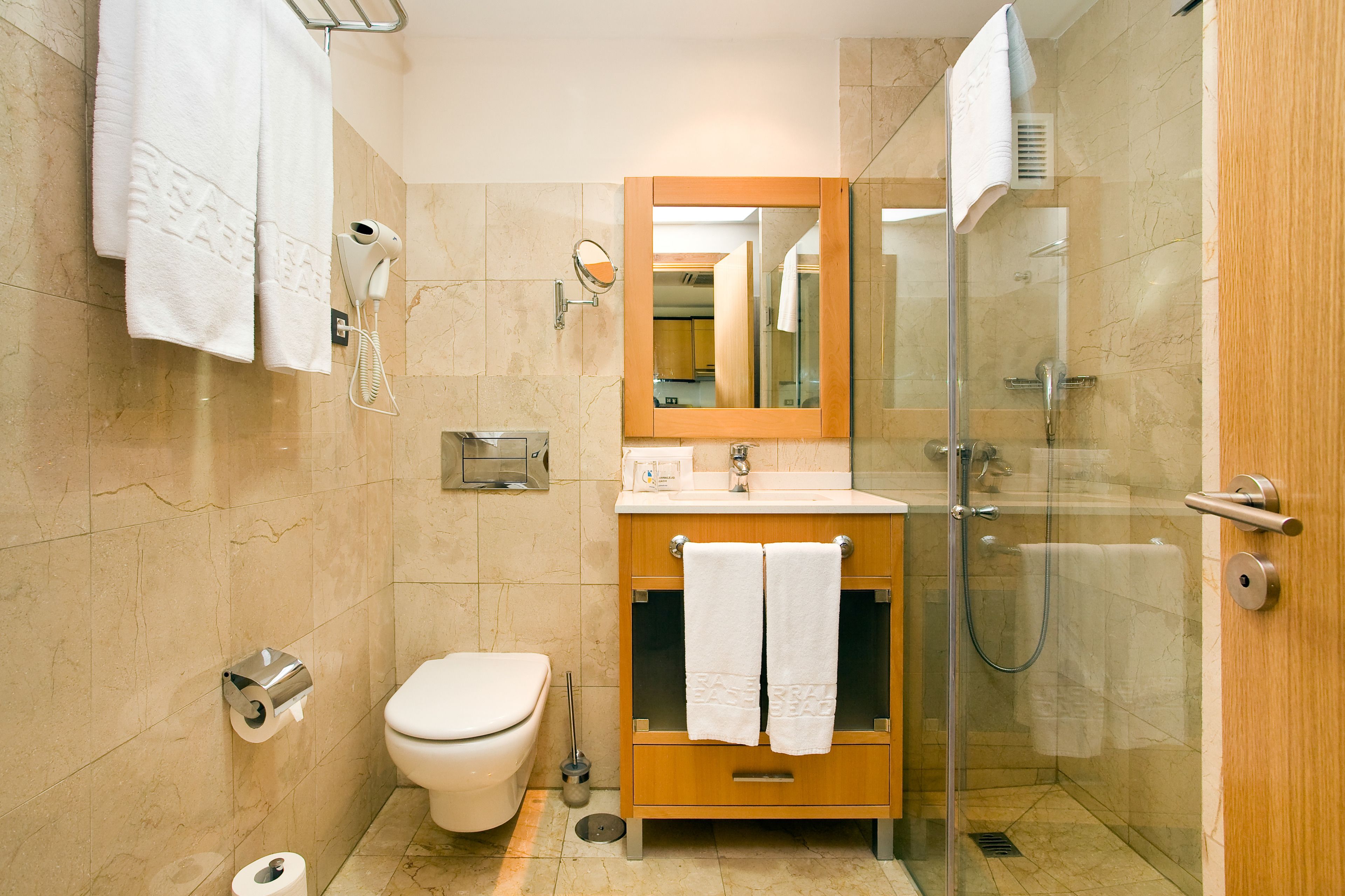 A bathroom with a toilet, sink, mirror, and shower.