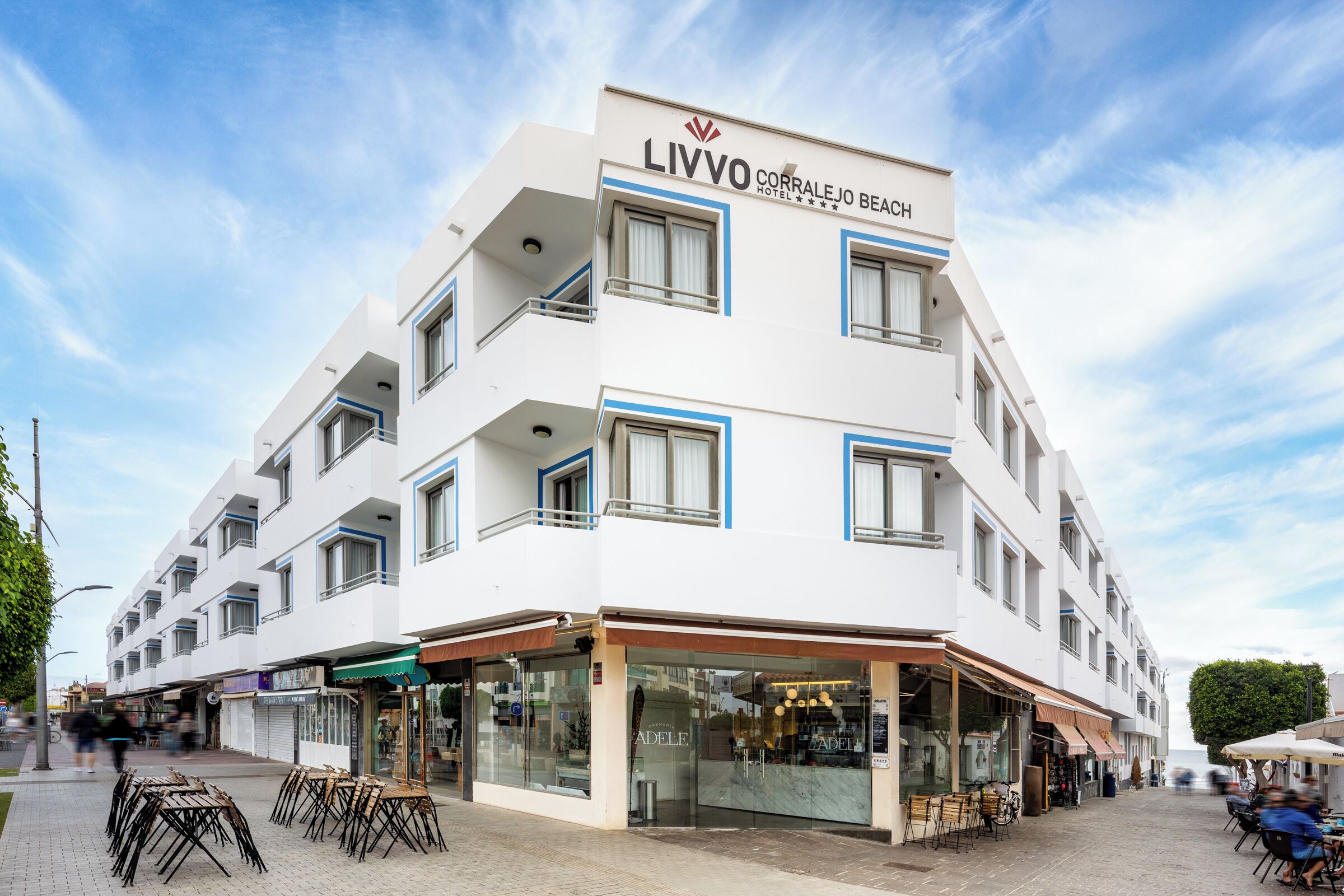 A multi-story hotel with a modern design, featuring balconies, large windows, and outdoor seating areas.