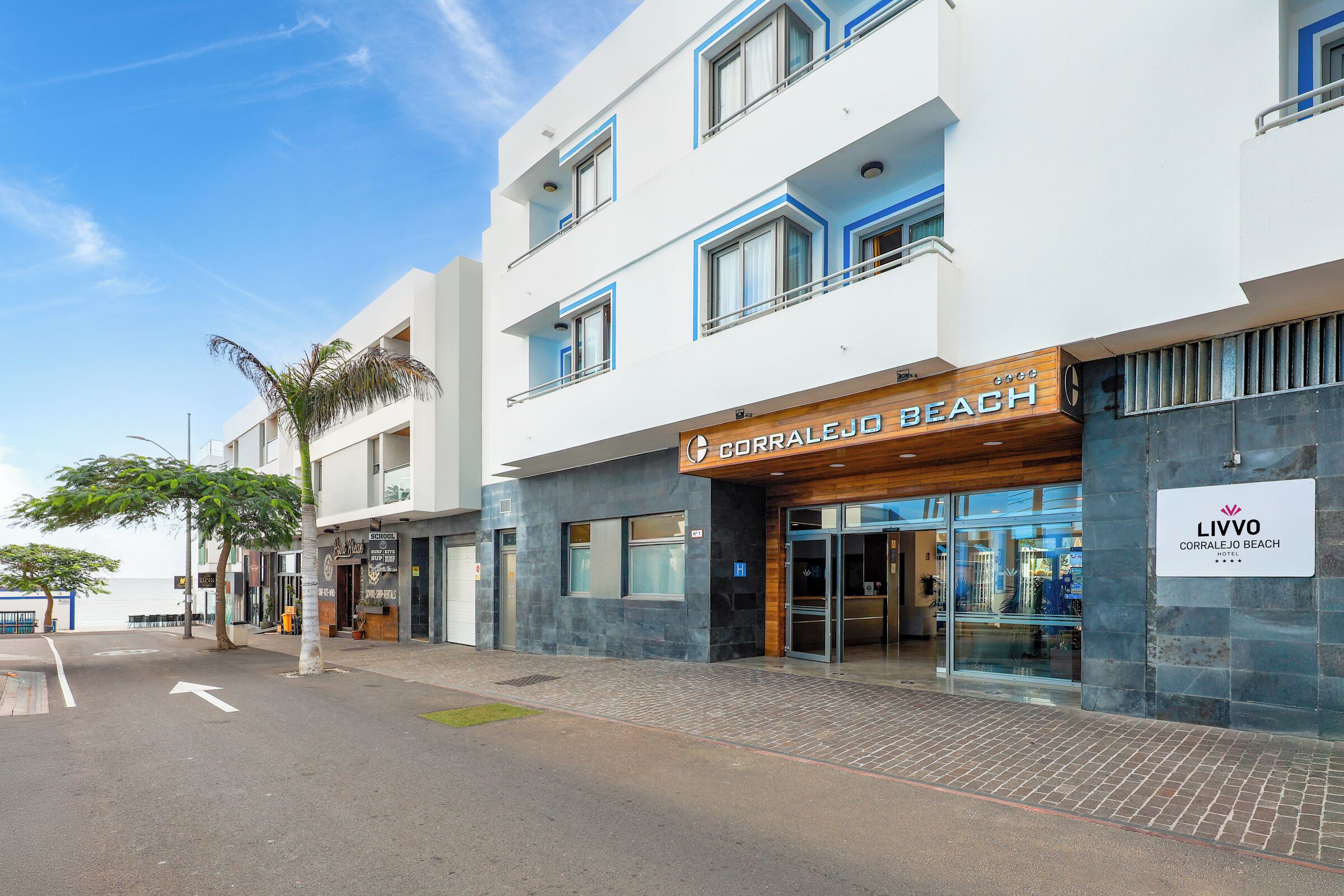 Un hotel moderno con fachada temática de playa, amplia entrada de vidrio y vista despejada a la calle.
