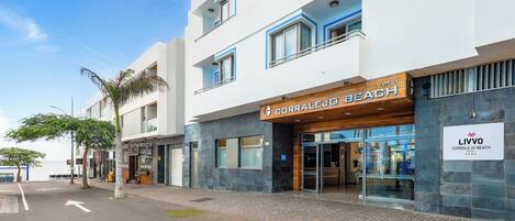 A modern hotel with a beach-themed facade, large glass entrance, and a clear view of the street.