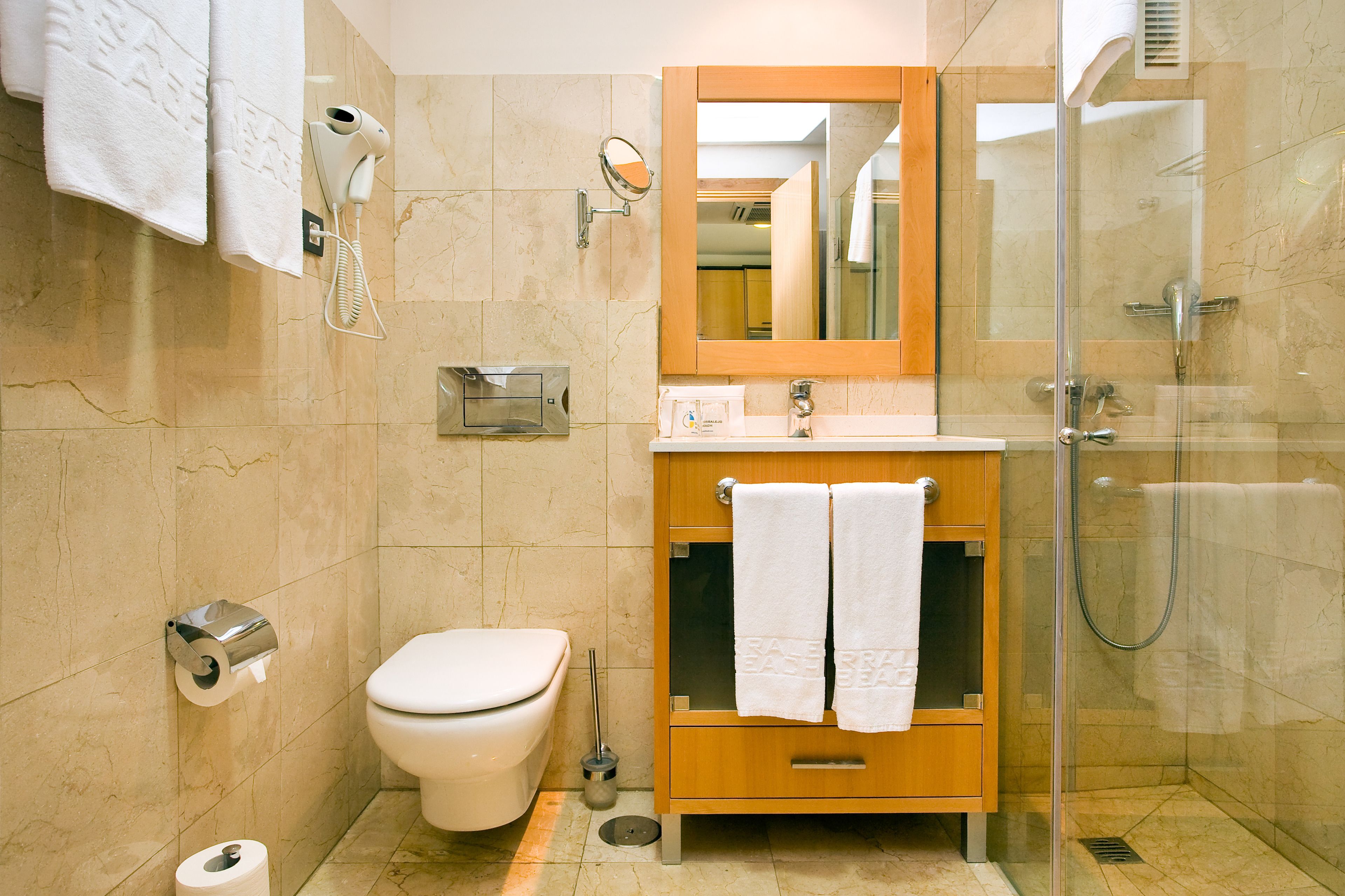 A bathroom with a toilet, sink, mirror, and shower.