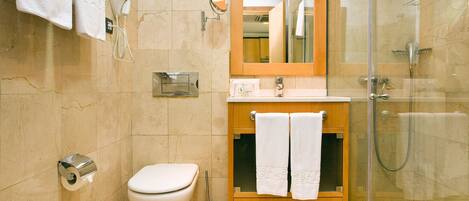 A bathroom with a toilet, sink, mirror, and shower.