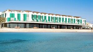Een modern hotel met een lange gevel, grote ramen en uitzicht op het strand.